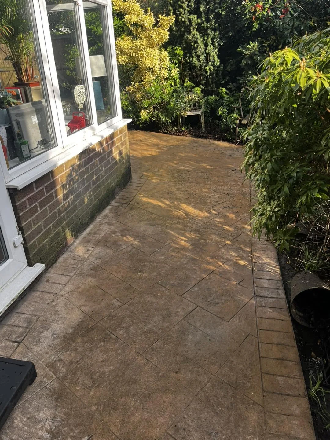 Clean patterned paving curving beside a conservatory and planting